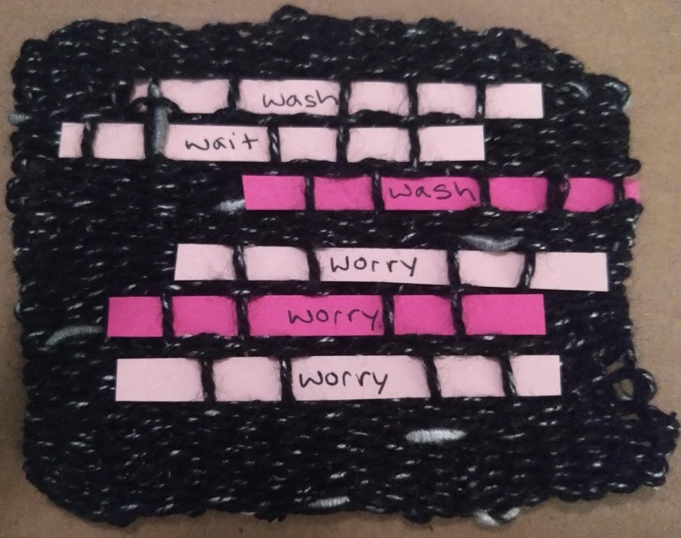 black yarn woven piece with 6 pink paper lines