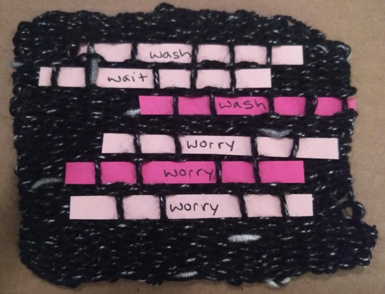 black yarn woven piece with 6 pink paper lines